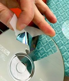 a person holding a cd in their left hand and pressing the disc out with one thumb