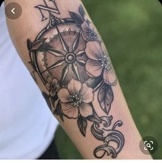 a woman's arm with a compass and flowers on it