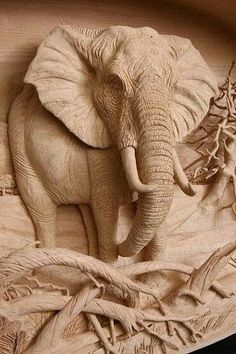 an elephant carved into the side of a wooden box with leaves and branches around it