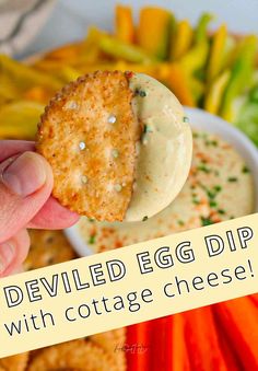 an egg dip with cottage cheese is being held up in front of a platter of vegetables