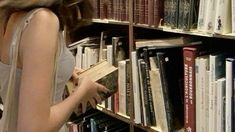 a woman standing in front of a book shelf filled with books