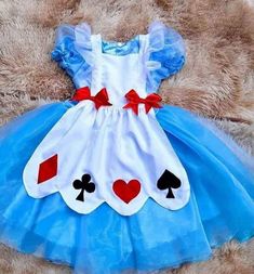 a teddy bear wearing a blue and white dress with playing cards on it's chest