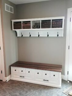 a mud room with white cabinets and drawers