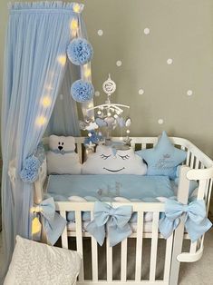 a baby crib with blue and white decorations on the bed, lights in the background