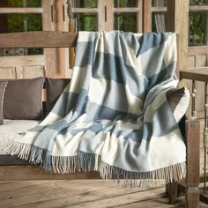 a blue and white checkered blanket sitting on top of a wooden bench next to pillows