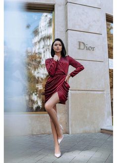 a woman posing in front of a store window wearing a red dress and white shoes