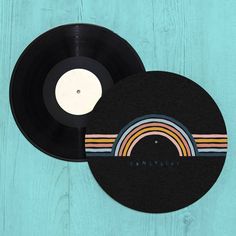 two vinyl records sitting next to each other on top of a wooden table with the word somewhere printed on it