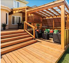 a wooden deck with chairs and an attached pergolan on the top level, in front of a house