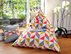 a triangle shaped pillow sitting on top of a wooden floor next to a vase filled with flowers