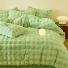 a bed with green comforter and pillows on it