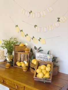 some lemons are sitting on a wooden table in front of a lemon sign and bunting