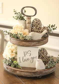 two tiered trays with flowers and signs on them sitting on top of a wooden table