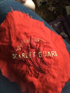 someone's jeans with an embroidered crab on the bottom and words that read scarlet guard