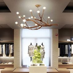 a chandelier hanging from the ceiling in a clothing store with mannequins and dresses on display