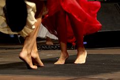 two women in red dresses are dancing on the floor with their feet up and legs down