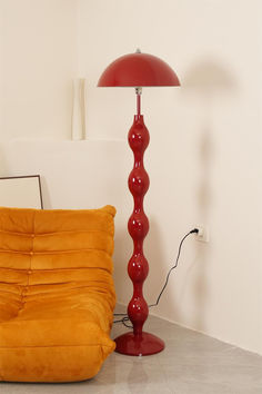 a red floor lamp next to an orange chair