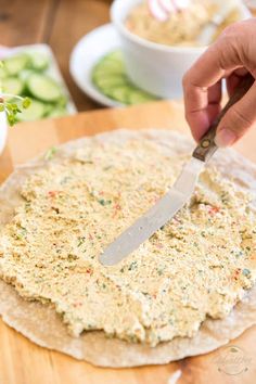 a person cutting up food on top of a wooden board with a knife in it