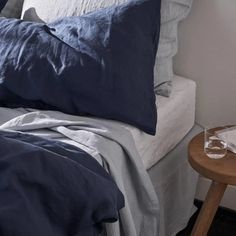 a bed with blue sheets and pillows on top of it next to a night stand