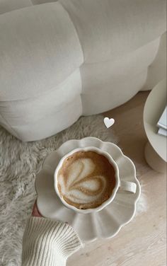 a cappuccino in a white cup on a saucer with a heart shaped decoration