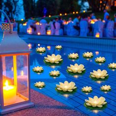 candles are floating on the water in front of a lantern and some lotuses with lights around them