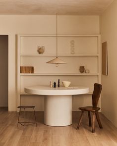 a dining room table with chairs and shelves on the wall behind it, in front of a wooden floor