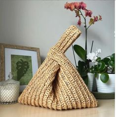 a woven bag sitting on top of a table next to a vase with flowers in it