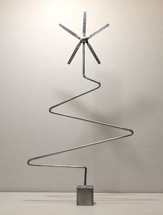 a metal christmas tree sitting on top of a white table