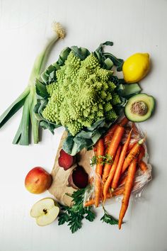 an assortment of fruits and vegetables on a white surface