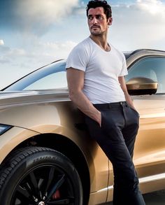 a man leaning on the side of a car with his hands in his pockets and looking at the camera