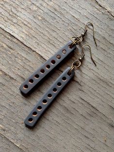 pair of black wooden earrings with holes in the middle on wood planks, closeup