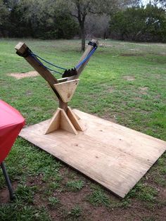 a wooden structure sitting on top of a lush green field next to a red table