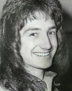 an old black and white photo of a man with long hair smiling at the camera