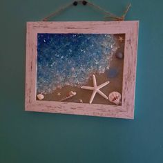 a frame hanging on the wall with starfish and seashells