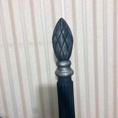 a black metal pole with a decorative design on it's top and bottom, next to a striped wall