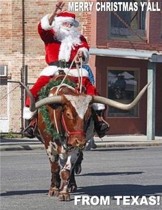 a man dressed as santa claus riding on the back of a bull down a street