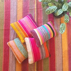 several colorful pillows and a potted plant on a striped table cloth