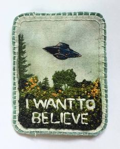 an embroidered patch with the words i want to believe on it and a spaceship in the sky