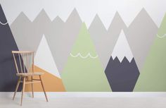 a chair sitting in front of a wall with mountains painted on it's sides