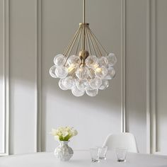 a white dining room table and chairs with a chandelier hanging from the ceiling