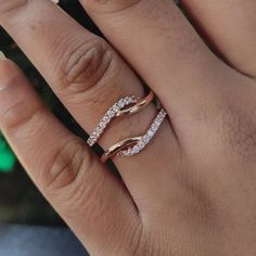 a woman's hand with two wedding rings on top of her finger and the other half