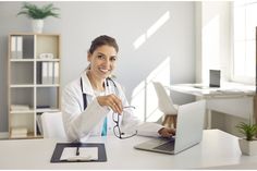 a woman sitting at a desk with a laptop computer in front of her, smiling