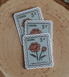 two stamps with flowers on them are sitting on a piece of wood