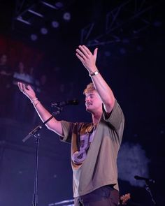 a man standing on top of a stage holding his hands up