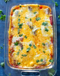 a casserole dish with meat, cheese and vegetables in it on a blue surface