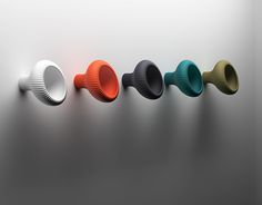 five different colored cups are lined up in a row on a gray surface, with one being turned upside down to the side