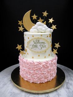 a pink and white cake with gold stars on the top that says welcome little star