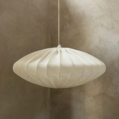 a white lamp hanging from a ceiling in a room with concrete walls and flooring