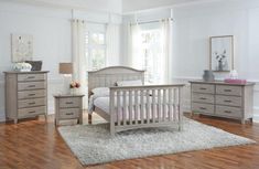 a bedroom scene complete with a bed, dressers and a baby's crib