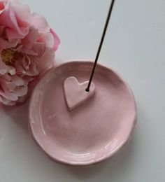 a pink bowl with a heart on it next to a flower