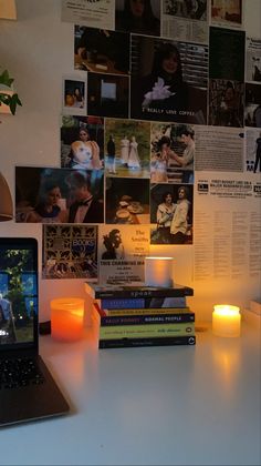 a laptop computer sitting on top of a desk next to a lit candle and books